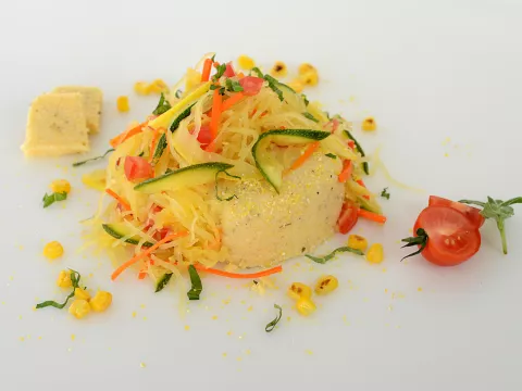 Mound of mascarpone polenta with squash ribbon spaghetti and vegetable garnish