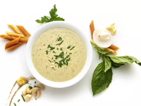 Bowl of vegan alfredo with herb and nut garnishes