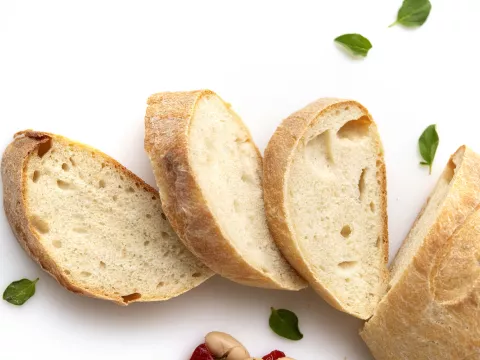 A baguette with three slices cut off and fanned out in front.