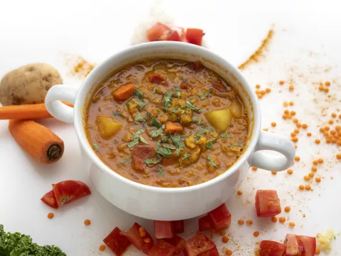 Bowl of lentil soup with carrot garnishes