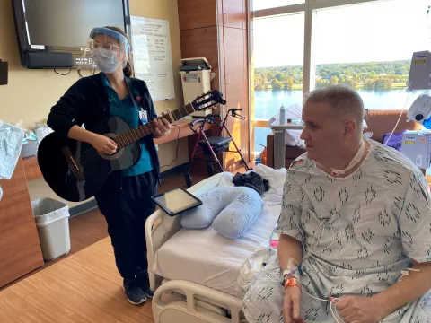 David Wilkinson, AdventHealth Orlando's first COVID lung transplant recipient, with music therapist Hannah Warner as she plays guitar.