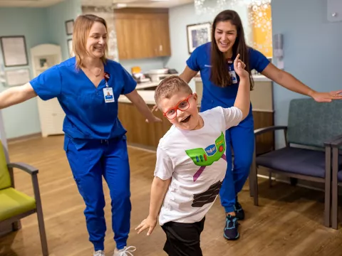 A boy wearing a buzz lightyear shirt with two AdventHealth employees.