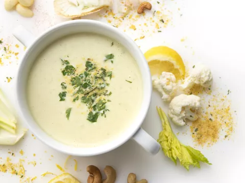 Bowl of cream of cauliflower soup with celery and breadcrumb garnish