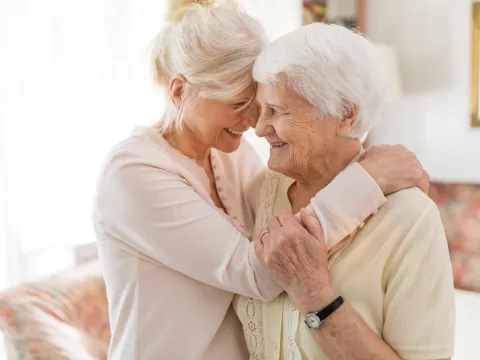 Two senior women hugging each other.