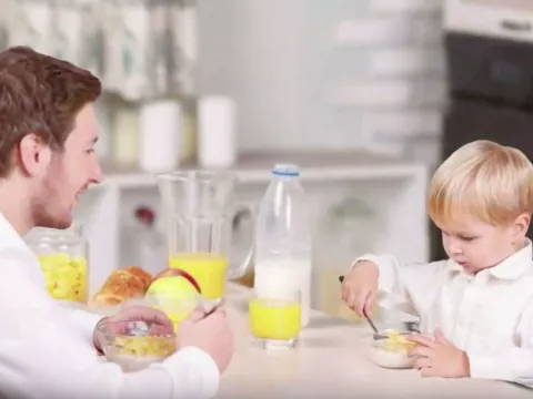 Father and young song eating breakfast at a table together.