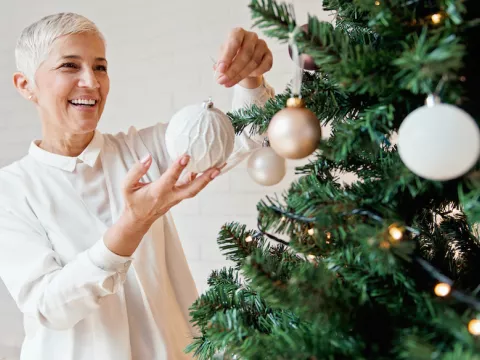 Woman hangs ornament in memory of loved one.