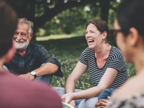 people sit in a circle on a beautiful day in the park