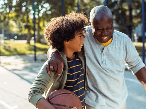 Grandfather and Grandson smiling on a basketball court.