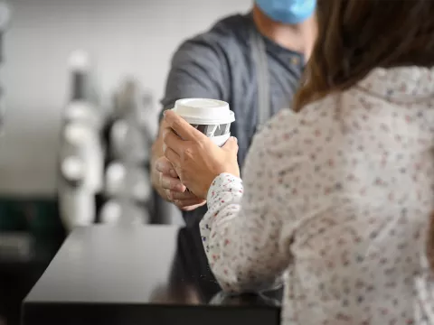 Foxtail barista handing a woman a cup of coffee.