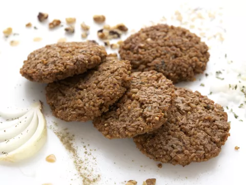 Five millet patties on white surface with onion garnish