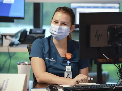 An AdventHealth employee working at a computer. 