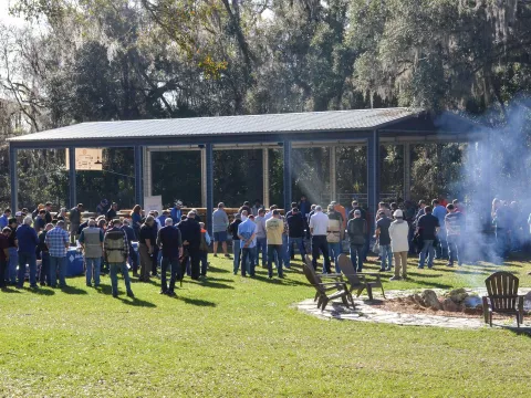 AHU Clay Shoot group have their heads bowed for prayer