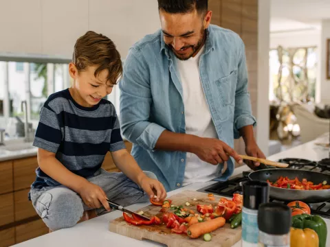 A father and son cook a healthy plant-based meal.