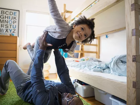 Child being held in the air with outstretched arms