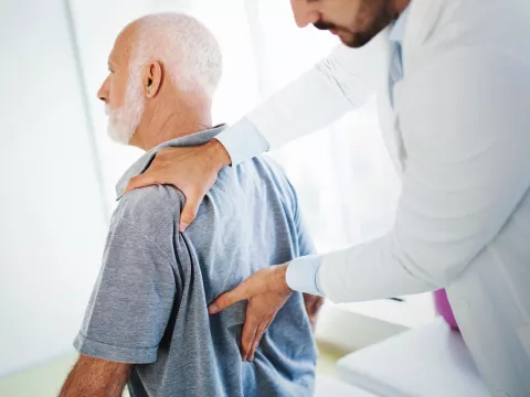 A doctor does a lower back exam on a patient. 