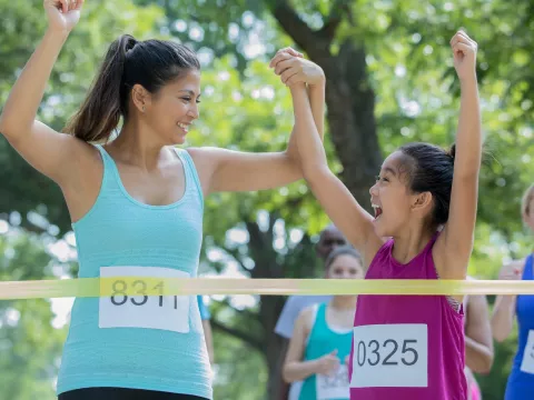 A mom and daughter cross the finish line at a 5k together.