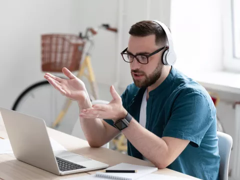 An adult man talks to his work team using a remote meeting