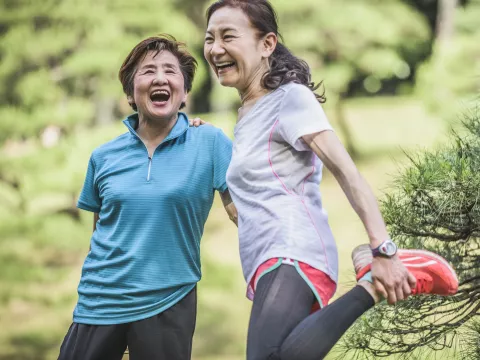 Two women laughing together while spending time outside.