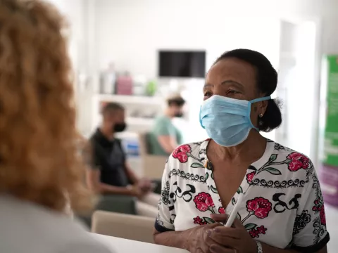 A woman visiting a medical provider wearing a mask.