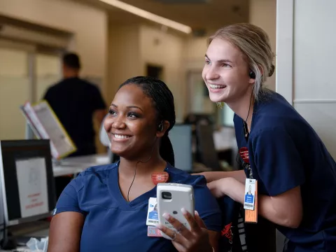 Two nurses from AdventHealth, smiling and looking to the left. 