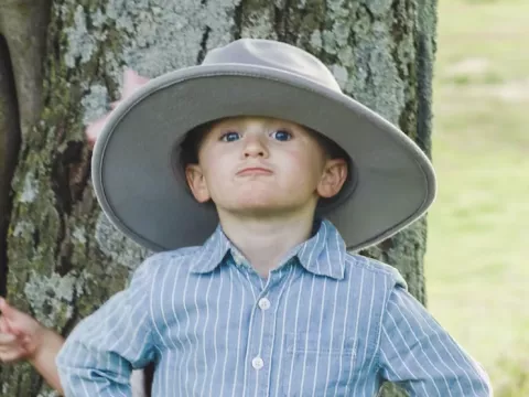 Jax Warren standing in front of tree with large hat