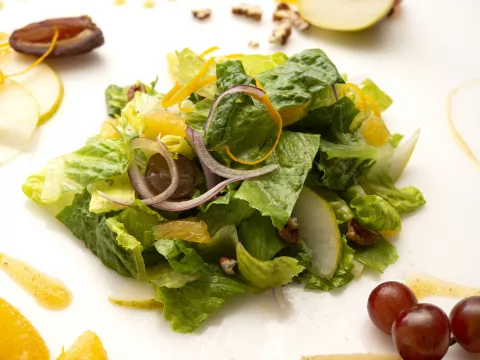 Mound of romaine salad with grape, orange, and apple garnishes