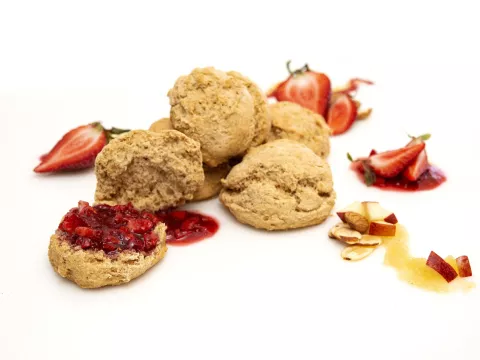 a pile of five fresh baked biscuits, topped with strawberry puree and surrounded by strawberry slices