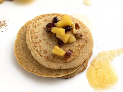 Stack of whole wheat pancakes with fruit and applesauce garnish