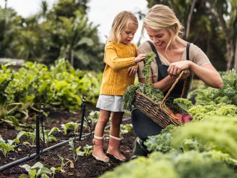 woman gardens with her young daughter