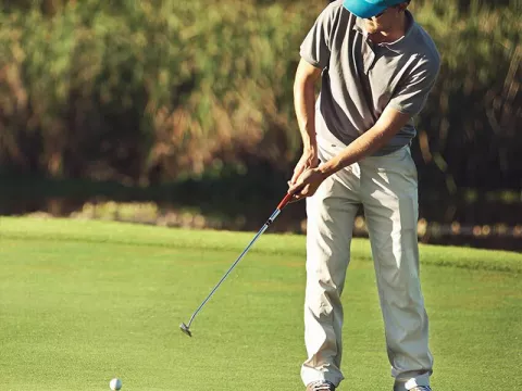 man in blue hat playing golf