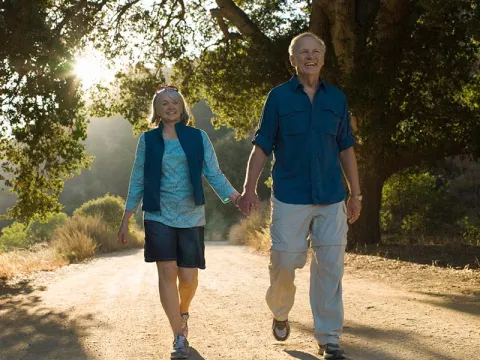 Older couple walking on a dirt road by trees