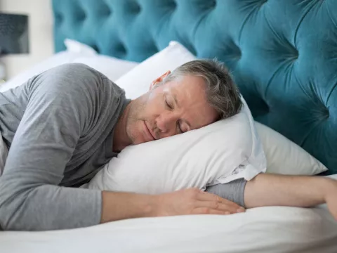 Man taking a nap in bed at home.