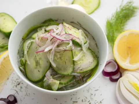 Bowl of cucumber-dill relish with lemon and cucumber garnishes