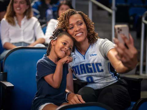 Mother and daughter taking selfie at Orlando Magic game.