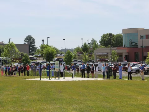 AdventHealth staff are gathered outside of a hospital praying.