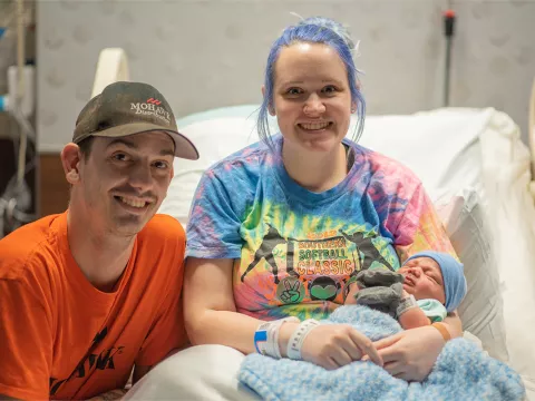 A couple at a hospital's bed with their new born baby.