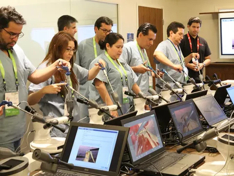 Professionals performing laparoscopic simulations in a Nicholson Center Lab Boardroom.