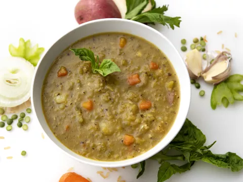 Bowl of split pea soup with onion and green garnishes