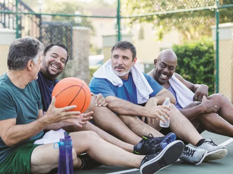 A group of men sitting down with a basket ball.