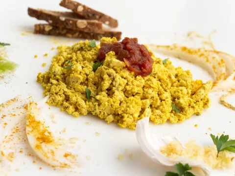 Scrambled tofu on white surface with toast garnish