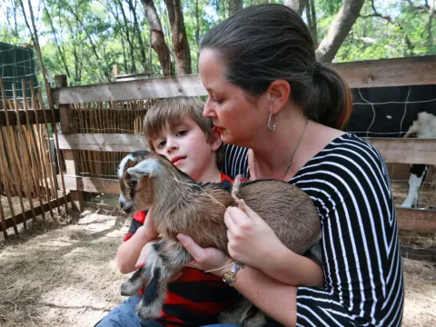 Cameron Munoz and one of her sons snuggle a baby goat at Puzzle Ranch in Sorrento, Florida.