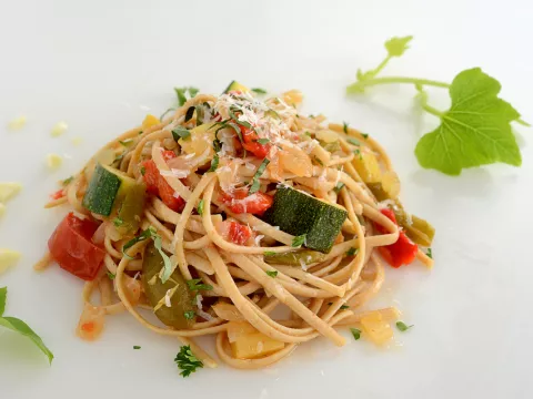 Mound of whole wheat pasta and veggies with leave garnish