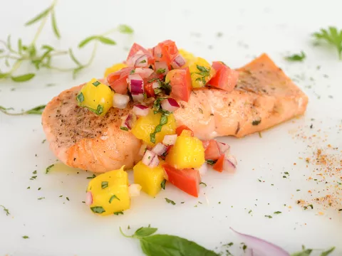 A salmon filet topped with tomato-mango salsa