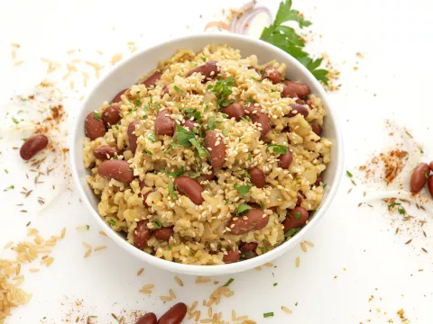 Bowl of beans and rice with grain sprinkled decoratively by bowl