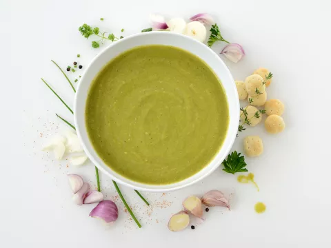 Bowl of asparagus soup with floral decoration beside bowl