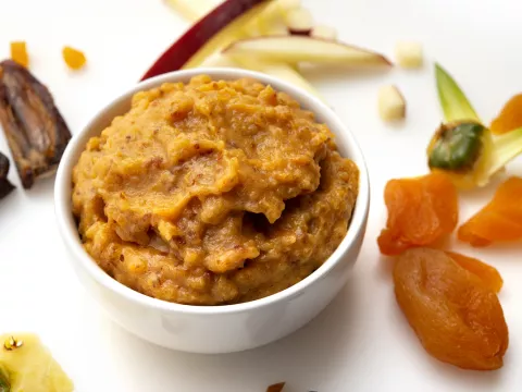 White bowl of apricot jam with dried fruit garnishes