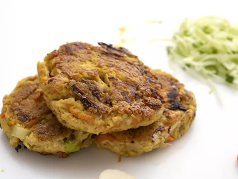 Three tofu yung patties on white surface with shredded zucchini garnish