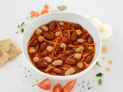 Bowl of Tuscan bean stew with cracker and tomato garnishes