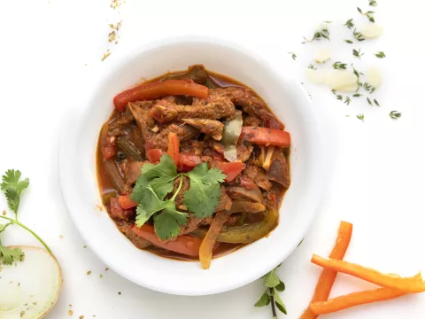 Bowl of ropa vieja stew with parsley and carrot garnishes