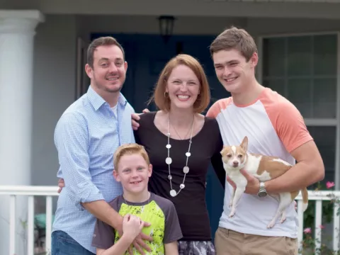 Family laughing in front of house